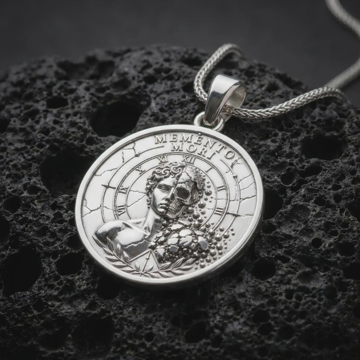 Polished sterling silver Memento Mori necklace displayed on dark volcanic stone, highlighting the classical split-face sculpture, exposed skull relief, Roman numeral dial, and detailed circular medallion.