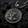 Load image into Gallery viewer, Oxidized sterling silver Memento Mori pendant on black volcanic rock, featuring a half-human half-skull portrait, Roman numeral clock markings, cracked stone details, and engraved Memento Mori lettering.
