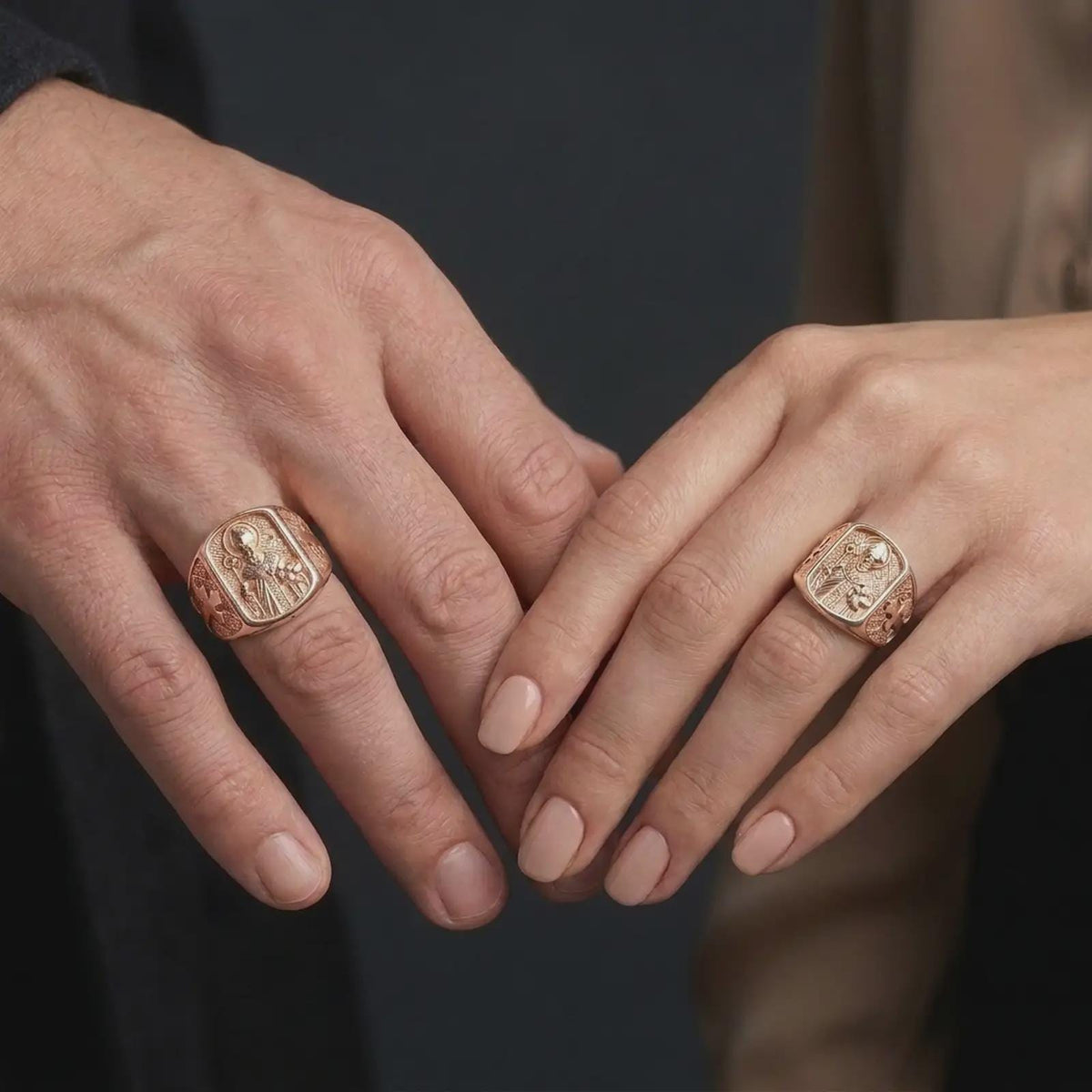 Rose gold plated 925 sterling silver matching St Nicholas religious signet rings worn on the fingers of a man and woman together, highlighting sculpted bishop figures, circular halos, ornate vestments, pastoral staffs, symbolic three-ball books, and coordinated rose gold plated finishes.