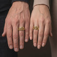 Load image into Gallery viewer, Gold plated 925 sterling silver matching Freemason rings worn on the fingers of a man and woman together, featuring sculpted hands surrounding Masonic Square and Compasses symbols, textured band backgrounds, and coordinated warm gold plated finishes.
