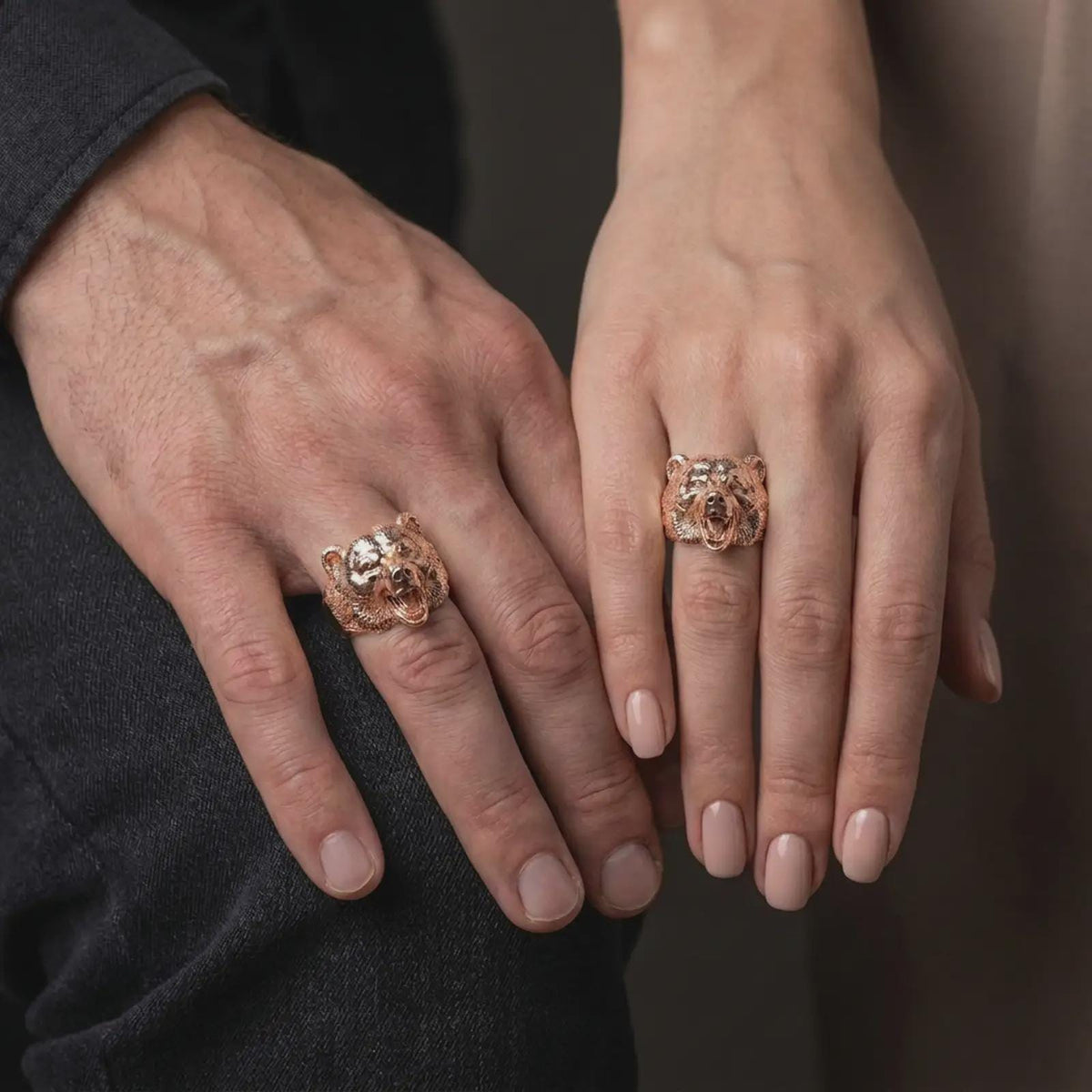 Rose gold plated 925 sterling silver matching bear head statement rings worn on the fingers of a man and woman together, highlighting fierce roaring bear sculptures, lifelike fur textures, open jaws, sculpted ears, and coordinated rose gold plated finishes.