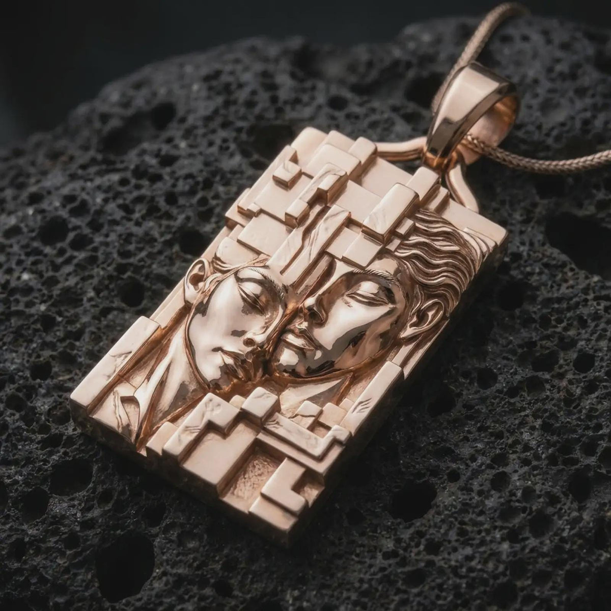 Rose gold plated Gemini zodiac necklace displayed on textured volcanic stone, showcasing the sculpted twin portraits, detailed facial features, layered geometric frame, and symbolic duality-inspired design.