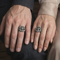 Load image into Gallery viewer, Oxidized sterling silver Masonic skull ring worn on a finger, showing the prominent skull face, Square and Compasses symbol with the letter G, and elaborate eagle wing details along the sides.
