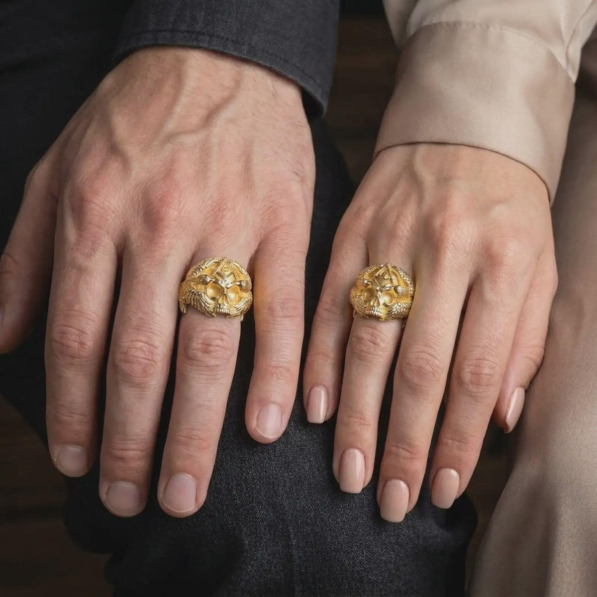 Gold plated Masonic skull ring worn on a finger, highlighting the dimensional skull face, raised Freemason Square and Compasses emblem, flowing eagle feather details, and distinctive biker-inspired jewelry design.