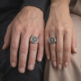 Load image into Gallery viewer, Oxidized sterling silver compass rose ring worn on the finger, showing the prominent eight-point compass star, dark recessed circular dial, engraved direction letters, and bold men's signet ring profile.
