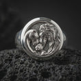 Load image into Gallery viewer, Polished sterling silver lion family ring displayed on dark volcanic stone, highlighting the detailed lion mane, gentle lioness portrait, small lion cub, and textured round signet face.

