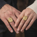 Load image into Gallery viewer, Gold plated winged dragon ring worn on the finger, highlighting the mythical dragon centerpiece, detailed scales, curved tail, shield-shaped frame, and powerful fantasy-inspired men's jewelry aesthetic.
