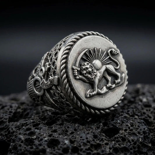 Oxidized sterling silver Persian Lion and Sun signet ring on black volcanic rock, featuring the historic Shir o Khorshid emblem, sword-bearing lion, radiant sun, and twisted rope border.