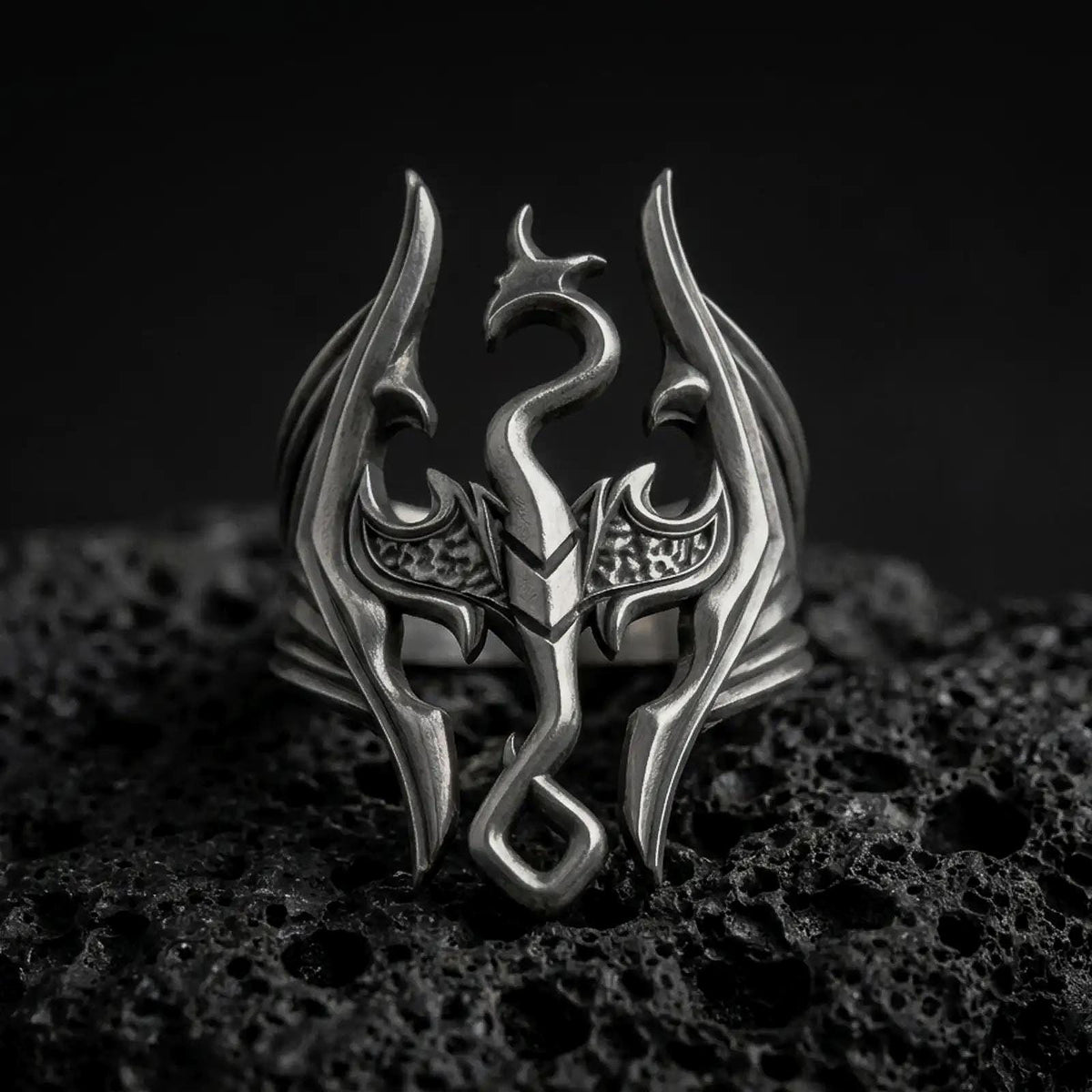 Oxidized sterling silver Skyrim Dragonborn ring on black volcanic rock, featuring the iconic dragon emblem with sweeping wings, an elongated serpentine neck, and an openwork fantasy design.
