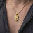Load image into Gallery viewer, Gold plated leopard pendant worn around the neck, highlighting the sculpted stalking big cat, detailed spotted fur, curved tail, shield-shaped frame, and bold masculine wildlife jewelry design.
