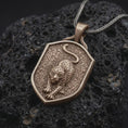 Load image into Gallery viewer, Bronze leopard pendant necklace on black volcanic stone, featuring a prowling spotted leopard with extended front paws, curved tail, textured shield-shaped background, and braided silver chain.
