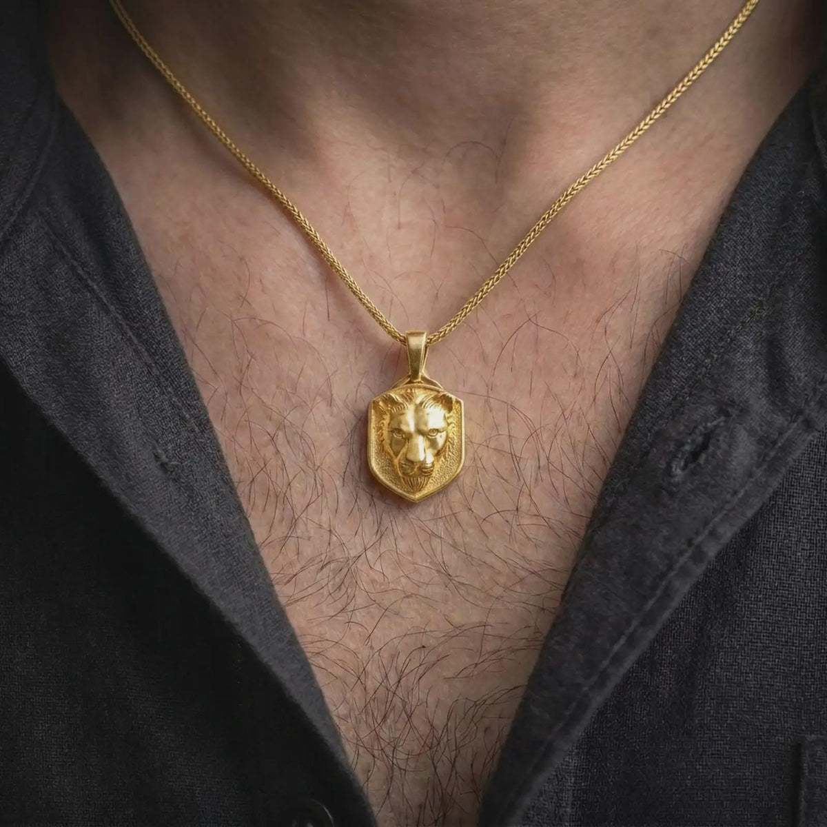Gold plated female lion pendant worn around the neck, highlighting the sculpted lioness face, refined animal details, shield-style outline, and symbolic big cat jewelry aesthetic.