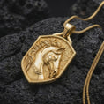 Load image into Gallery viewer, Gold plated horse head necklace resting on black textured stone, featuring a raised equestrian horse sculpture with flowing mane, elegant muzzle, ornamental bridle, and shield-shaped pendant design.
