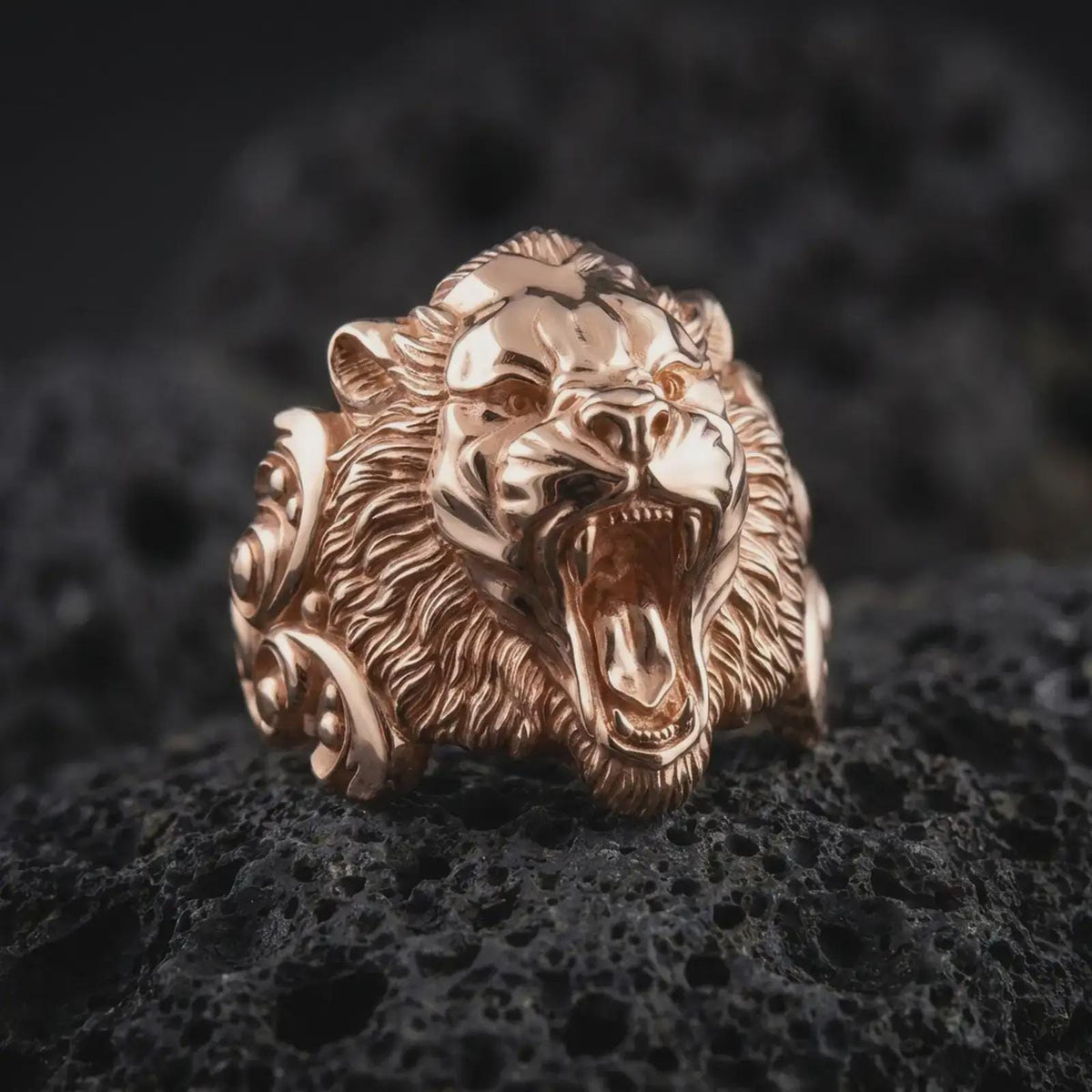 Rose gold plated tiger head statement ring displayed on black textured stone, featuring sculpted fangs, roaring mouth, detailed facial contours, and strong ornamental shoulders.