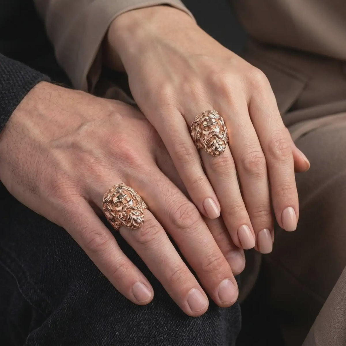 Rose gold plated sterling silver matching Poseidon rings worn on the fingers of a man and woman together, highlighting detailed Greek mythology portraits, wavy hair, dimensional beards, and coordinated rose gold finishes.