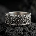 Load image into Gallery viewer, Oxidized 925 sterling silver Valknut Viking ring displayed on black volcanic rock, featuring raised interlocking Norse triangle symbols, dark textured recesses, polished silver borders, and a wide geometric band.
