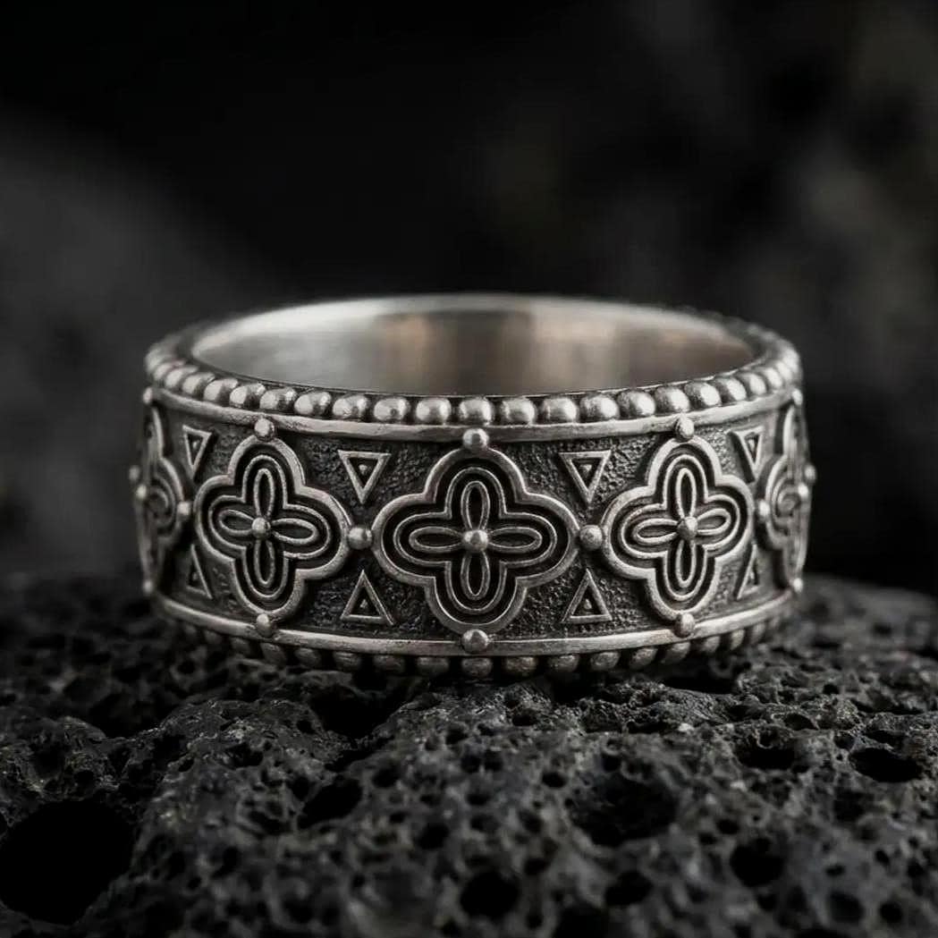 Oxidized 925 sterling silver Valknut Viking ring displayed on black volcanic rock, featuring raised interlocking Norse triangle symbols, dark textured recesses, polished silver borders, and a wide geometric band.