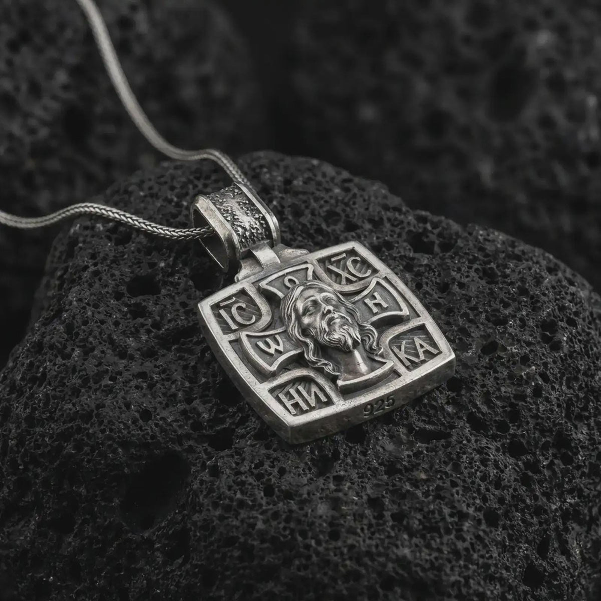 Oxidized Silver Saint George Slaying Dragon pendant on black volcanic rock, featuring the warrior saint on horseback with a spear.