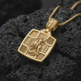 Load image into Gallery viewer, Gold Plated Saint George the Dragon Slayer necklace on black volcanic rock, featuring a detailed horse and rider relief with radiant corner patterns.
