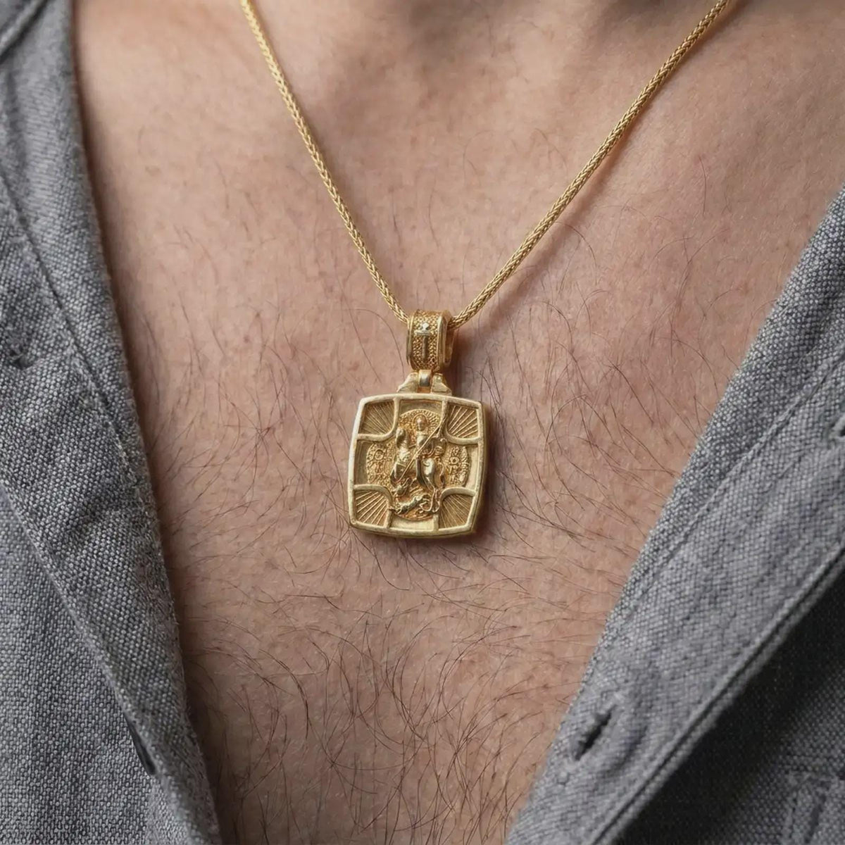 Gold Plated Saint George Dragon Slayer pendant worn on a man's chest with an open black shirt, displaying its sculptural Christian design.