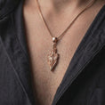 Load image into Gallery viewer, Rose gold plated 925 sterling silver matching fantasy dragon sword pendant necklaces worn by a man and woman together, highlighting sculpted mythical dragons, spread wings, detailed medieval blades, ornamental hilts, and coordinated rose gold plated finishes.
