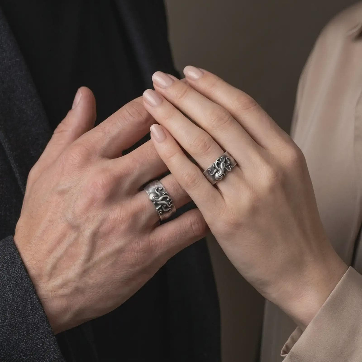 Oxidized 925 sterling silver matching octopus tentacle rings worn on the fingers of a man and woman together, featuring detailed curling tentacles, raised suction cups, sculpted octopus figures, wide bands, and coordinated dark oxidized silver finishes.