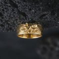 Load image into Gallery viewer, Gold plated 925 sterling silver octopus tentacle band displayed against textured black volcanic rock, featuring a raised sea creature sculpture, curling tentacles, detailed suction cups, flowing organic patterns, and warm gold plated finish.
