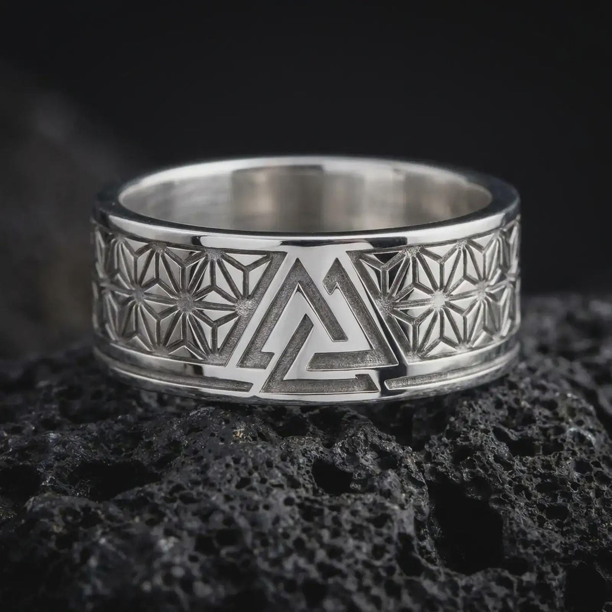 Polished Silver Viking symbol ring on black volcanic rock, highlighting the central interlocking triangle design and symmetrical hemp leaf motifs.