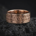 Load image into Gallery viewer, Rose Gold Plated Valknut ring resting on black volcanic rock, showing the wide band, raised borders, and detailed Asanoha-inspired patterns.
