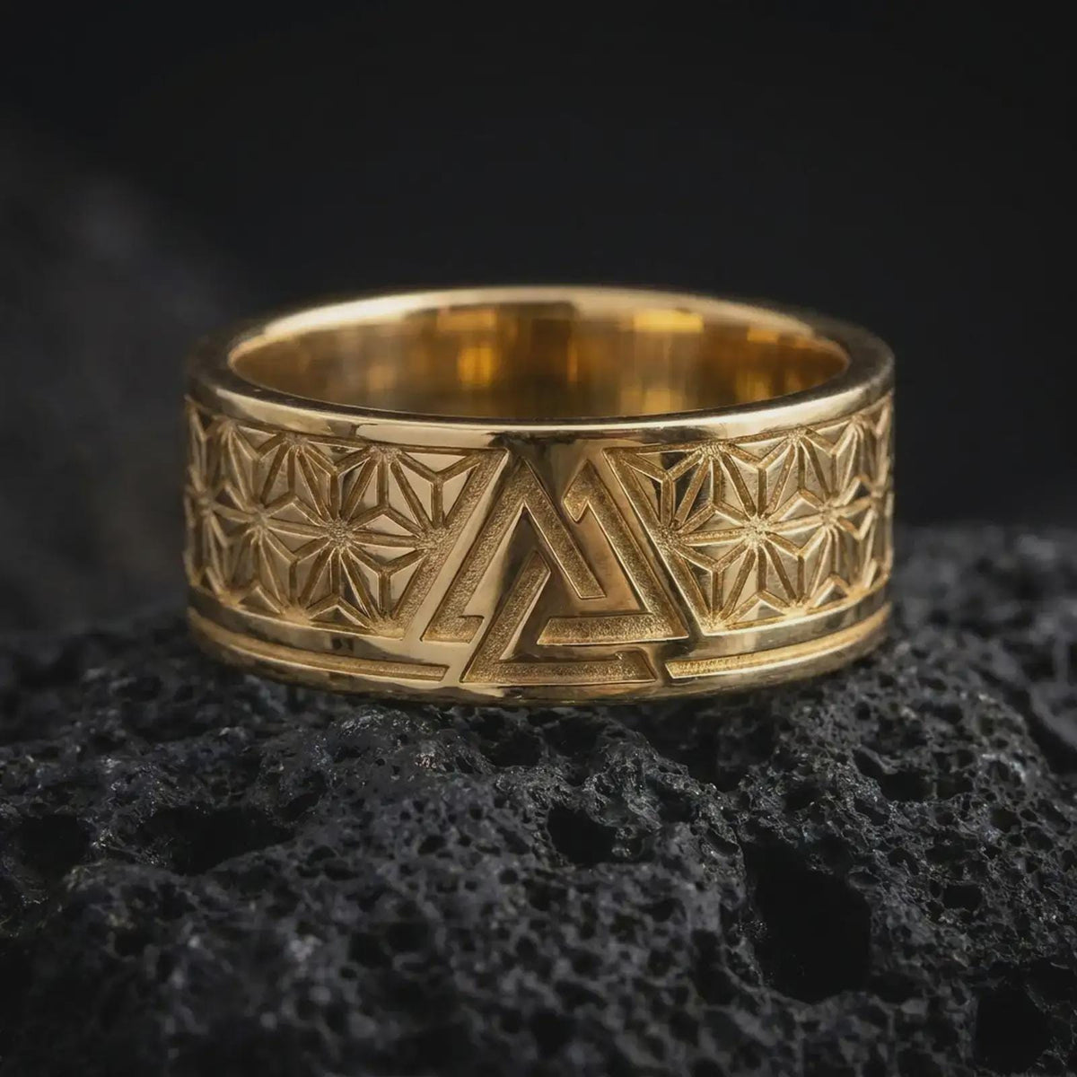 Gold Plated Valknut geometric band displayed on black volcanic rock, featuring angular Norse-inspired symbolism and repeating star-shaped engravings.