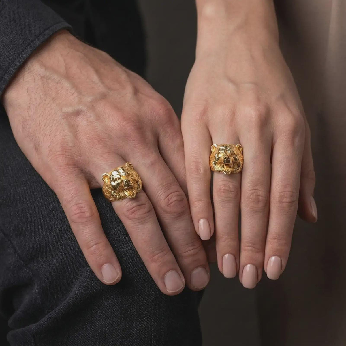 Gold plated 925 sterling silver matching roaring bear rings worn on the fingers of a man and woman together, featuring detailed three-dimensional wildlife sculptures, powerful bear faces, open mouths, sharp fangs, and coordinated warm gold plated finishes.