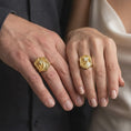 Load image into Gallery viewer, Gold plated 925 sterling silver matching eagle shield rings worn on the fingers of a man and woman together, featuring raised screaming eagle heads, detailed feather reliefs, sharp talons, geometric shield borders, and coordinated warm gold plated finishes.
