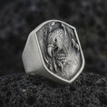 Load image into Gallery viewer, Oxidized 925 sterling silver eagle head signet ring displayed on textured black volcanic rock, featuring a screaming eagle with an open hooked beak, sharp talons, detailed feathers, shield-shaped face, and dark oxidized silver finish.
