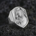 Load image into Gallery viewer, Polished 925 sterling silver screaming eagle ring resting on black volcanic stone, showcasing a fierce bird of prey with a curved open beak, sculpted feather textures, powerful claws, geometric shield border, and bright polished silver finish.
