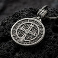 Load image into Gallery viewer, Oxidized Silver double sided Saint Benedict pendant on black volcanic rock, showing the Benedict medal cross with Latin initials and PAX inscription.
