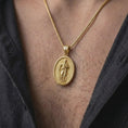 Load image into Gallery viewer, Gold Plated Saint Paul Catholic pendant worn on a man's chest with an open black shirt, displaying the haloed apostle and religious details.

