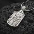Load image into Gallery viewer, Polished Silver Calvary Crucifixion necklace on black volcanic rock, highlighting three sculpted crosses and detailed biblical figures.
