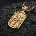 Load image into Gallery viewer, Gold Plated Golgotha pendant displayed on black volcanic rock, featuring the Crucifixion of Jesus with cloud reliefs and an architectural background.
