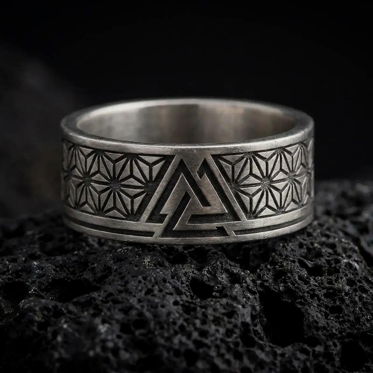 Oxidized Silver Valknut ring on black volcanic rock, featuring a stylized Norse triangular knot and intricate Asanoha geometric patterns.