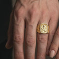 Load image into Gallery viewer, Gold Plated Saint Paul Apostle rings displayed on the fingers of a man and woman together, featuring the sculpted saint with his sword and book.
