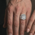 Load image into Gallery viewer, Polished Silver Saint Paul signet rings worn by a man and woman together, highlighting the rectangular religious relief and geometric side patterns.
