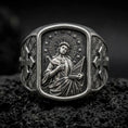 Load image into Gallery viewer, Oxidized Silver Saint Cecilia signet ring on black volcanic rock, featuring the patron saint of musicians holding a portable organ and martyr's palm.
