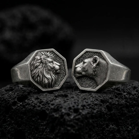 Oxidized Silver Lion and Lioness Ring Set on black volcanic rock, featuring matching octagonal signet rings with detailed wildlife portraits.